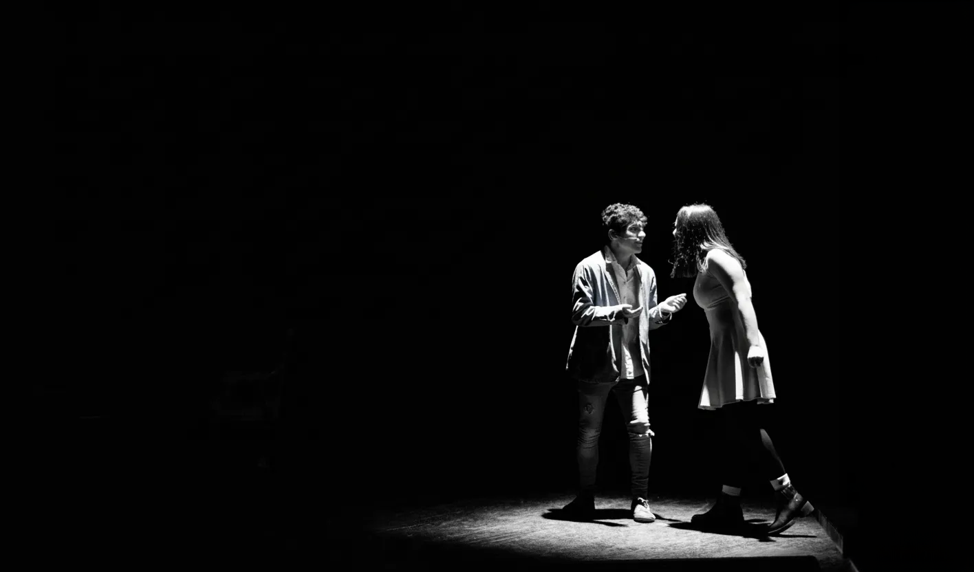 Black and white photo of teens rehearsing a dance routine on a stage.