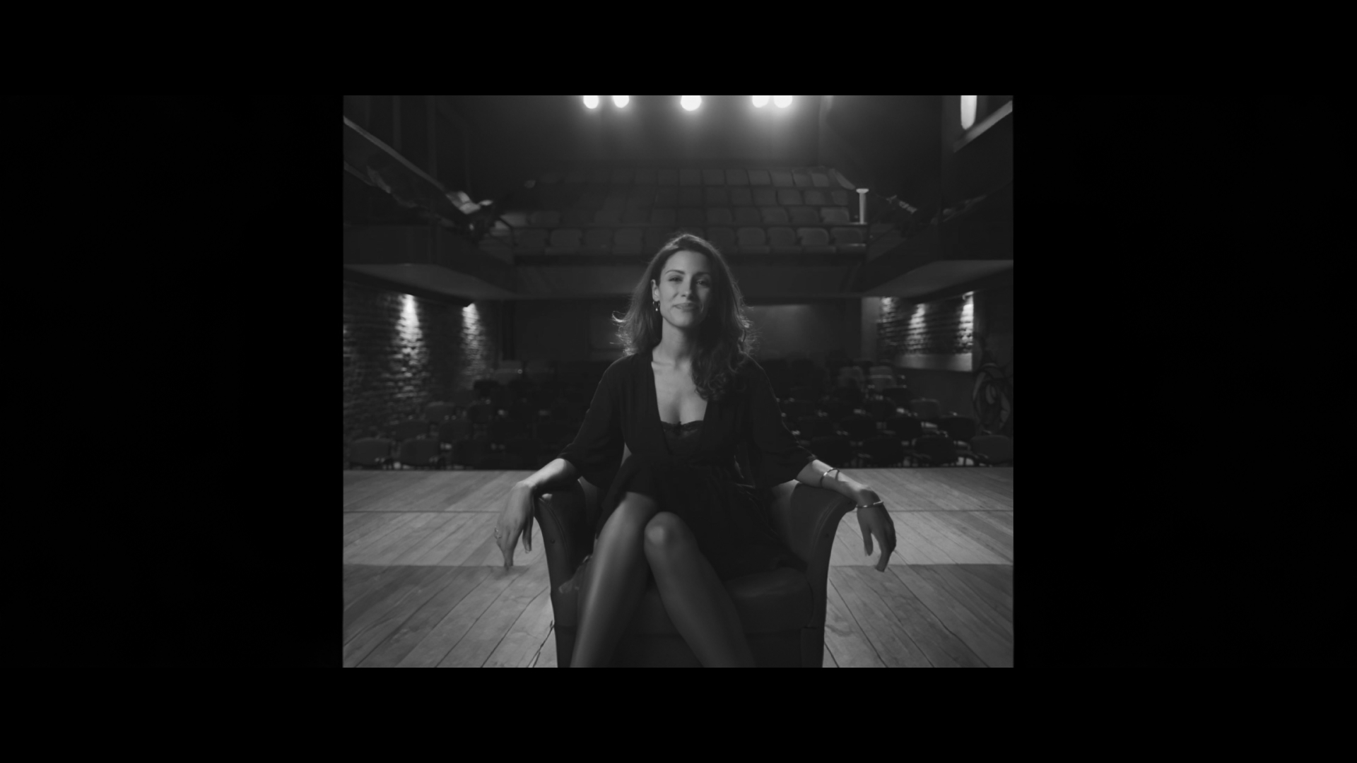Black and white portrait of a dance instructor posing in front of a dark background.